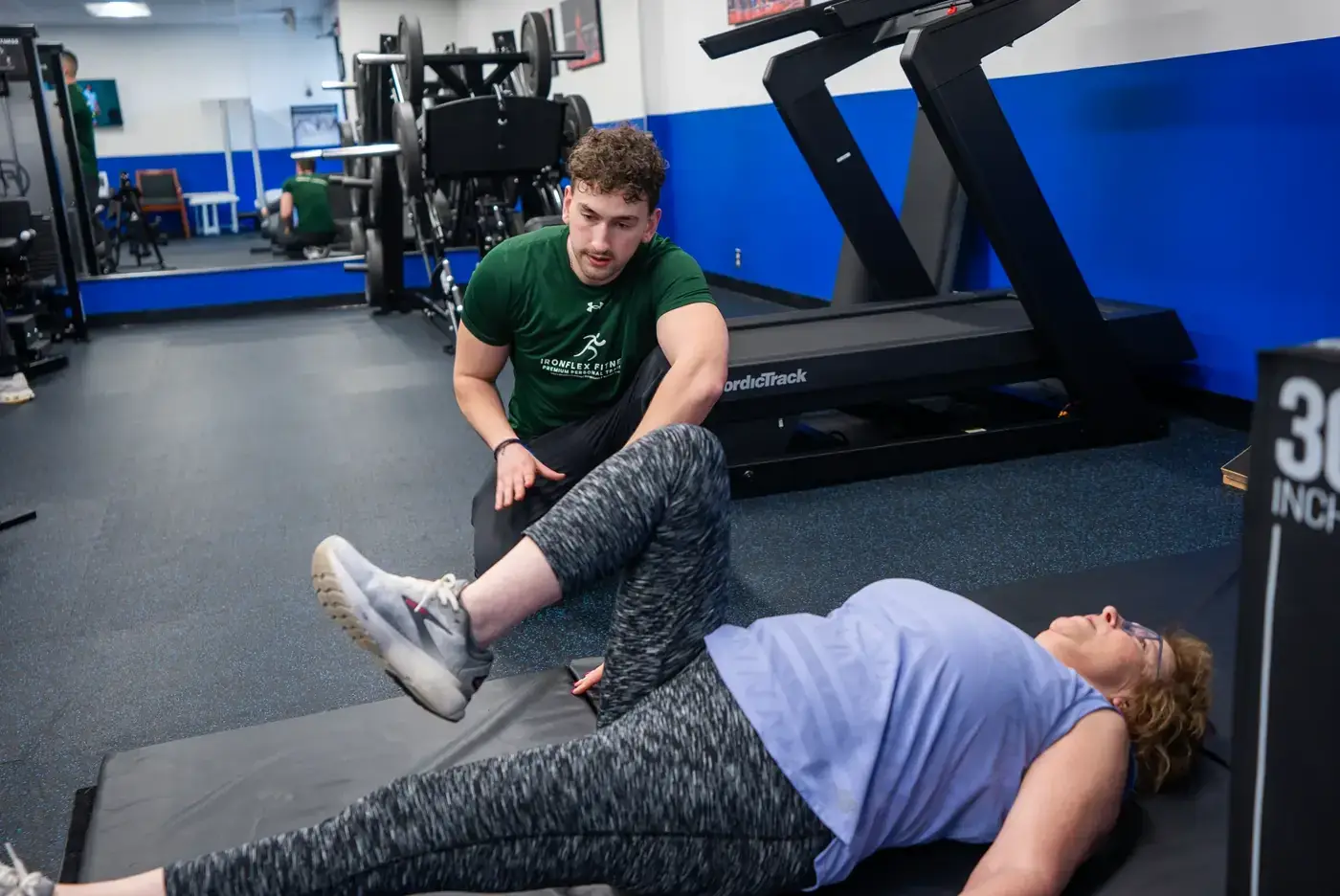 Trainer working through a client's leg mobility on the mat