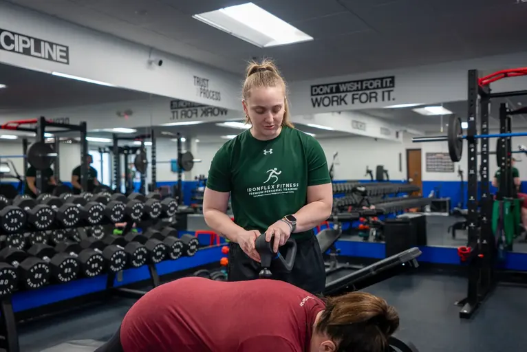 Trainer supporting a client on a chest-supported row