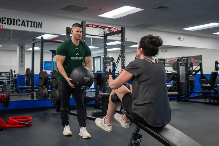 Trainer coaching a client through a seated press