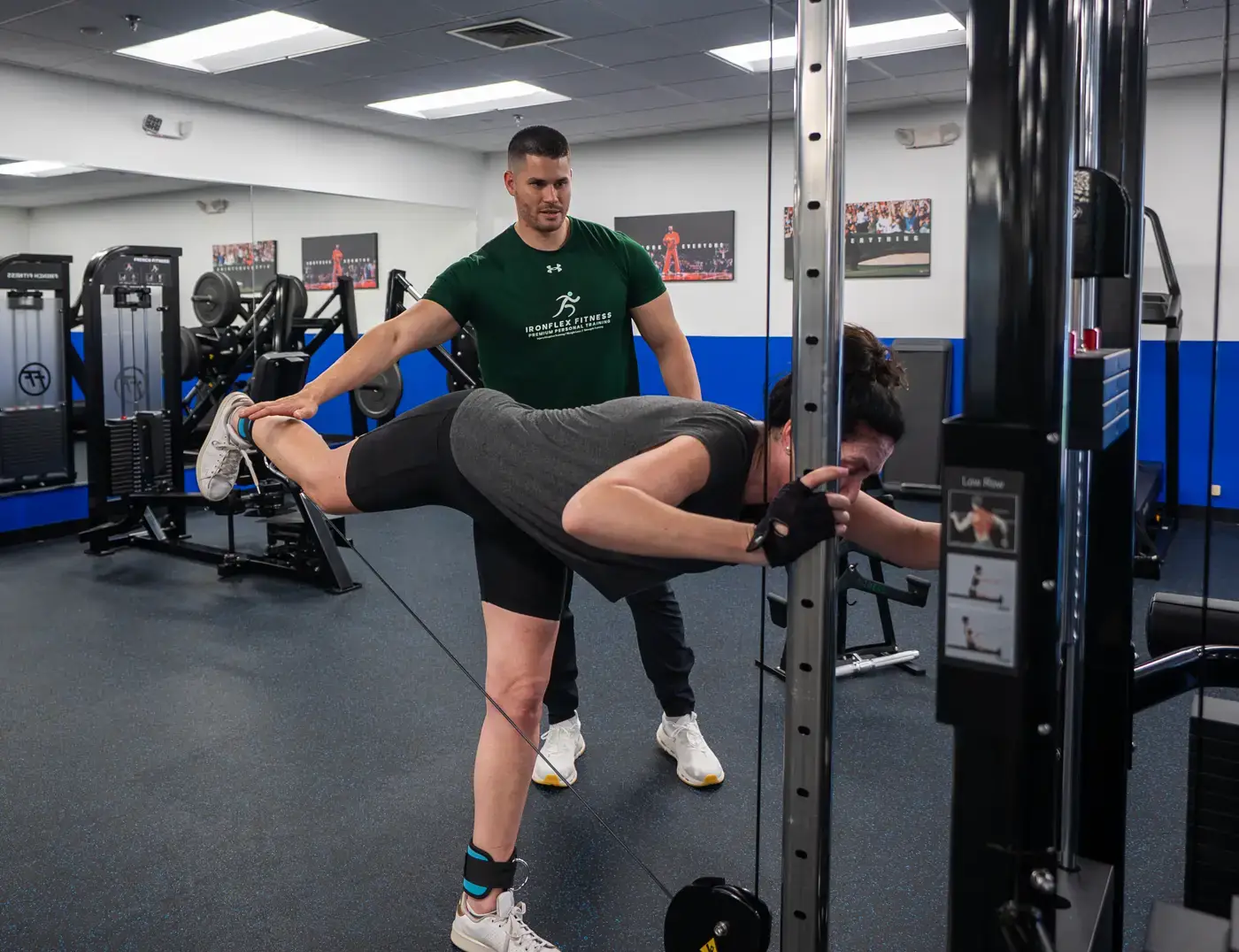 Trainer supporting a client through a standing hamstring exercise