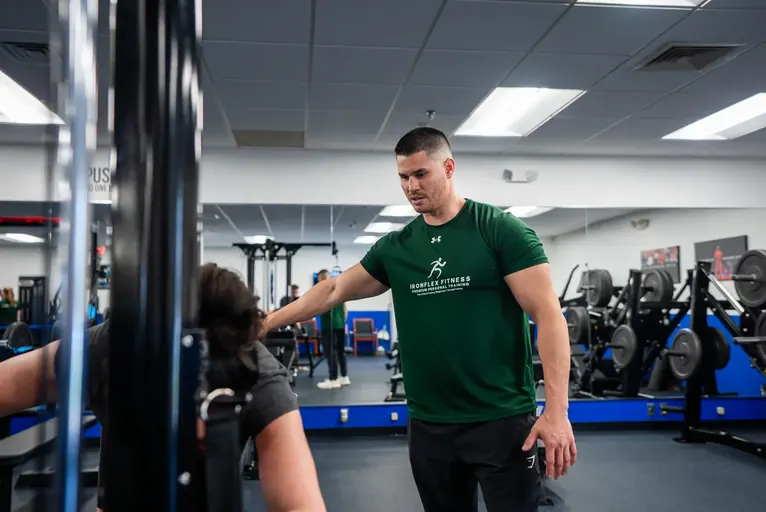 Trainer cueing a client on a cable machine