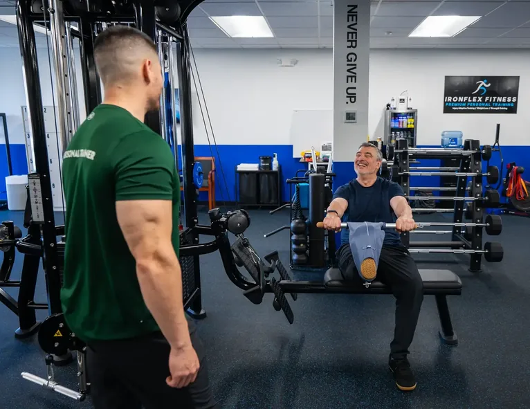 Trainer coaching an older client on a seated row