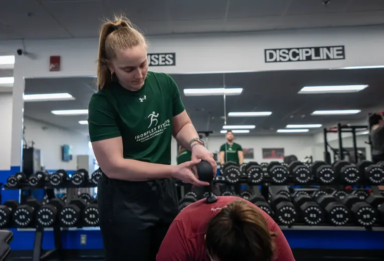 Trainer spotting a client on a dumbbell row