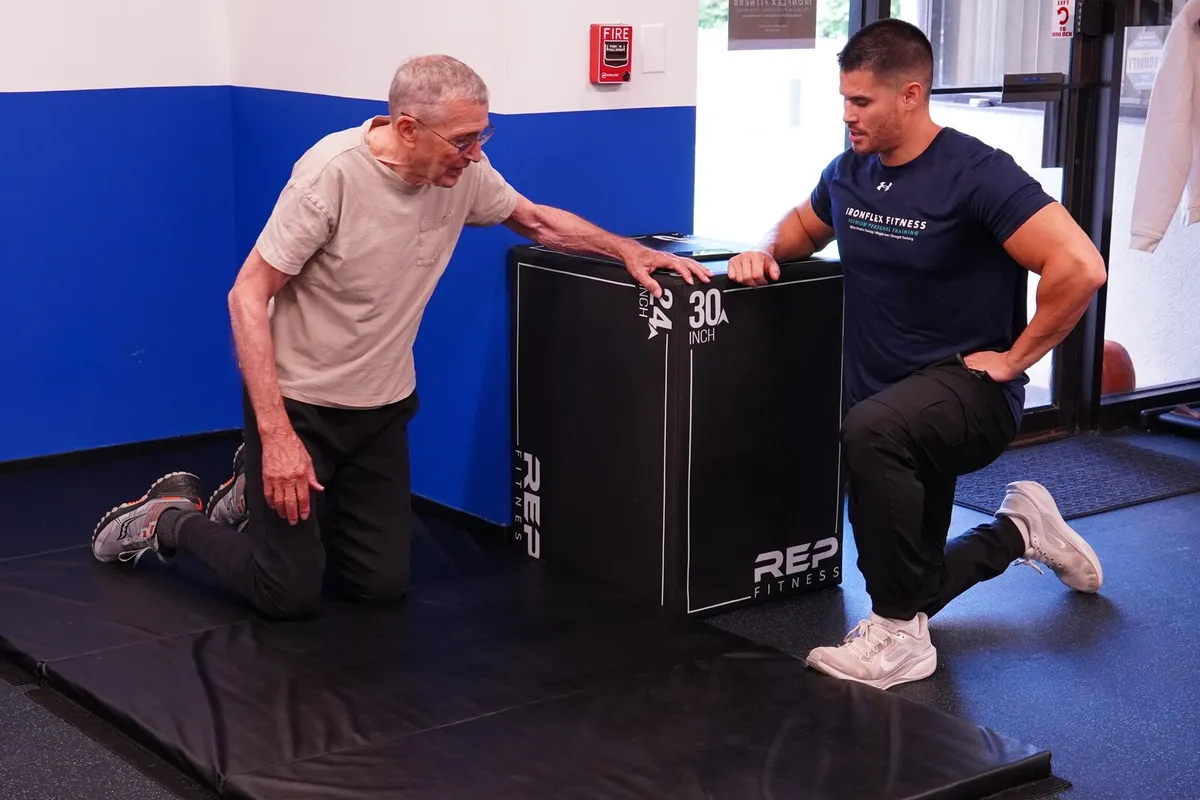 Coach walking an older client through a kneeling step-up
