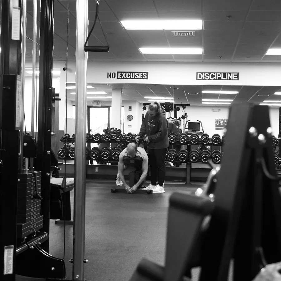 Gina Carroll coaching a client on the floor at IronFlex