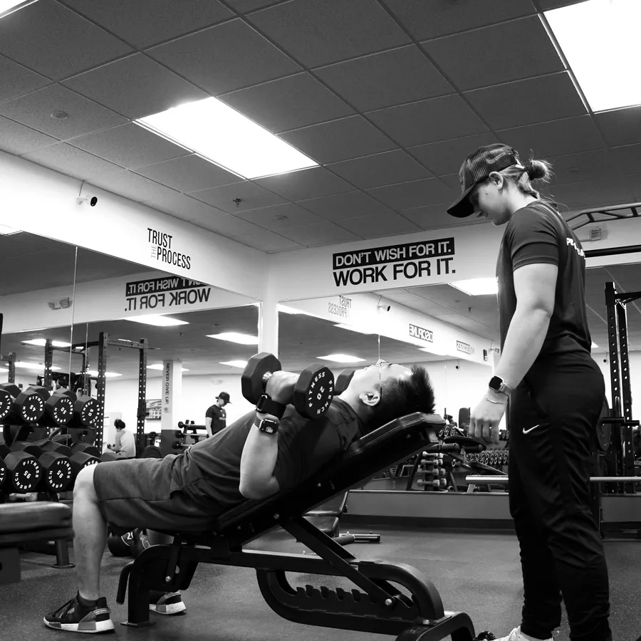 Gina Carroll coaching a client through an incline press at IronFlex