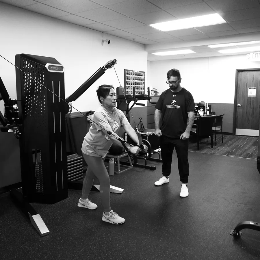 Michael O'Rourke coaching a client on the cable machine at IronFlex