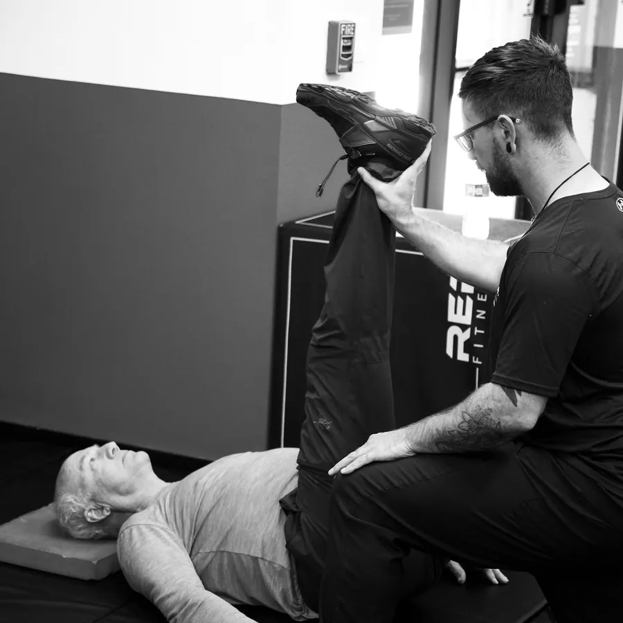 Michael O'Rourke guiding a client through a hamstring stretch at IronFlex